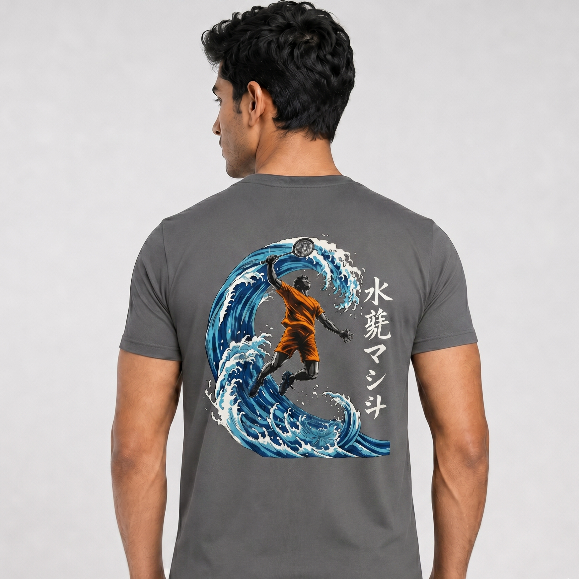 Person wearing a gray t-shirt with a graphic of a surfer on a wave and Japanese text.