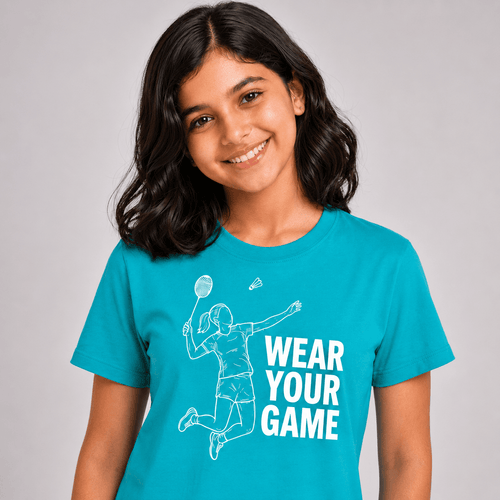 A smiling young woman with dark hair wearing a bright turquoise blue t-shirt with a white graphic of a badminton player and the text 'WEAR YOUR GAME'.