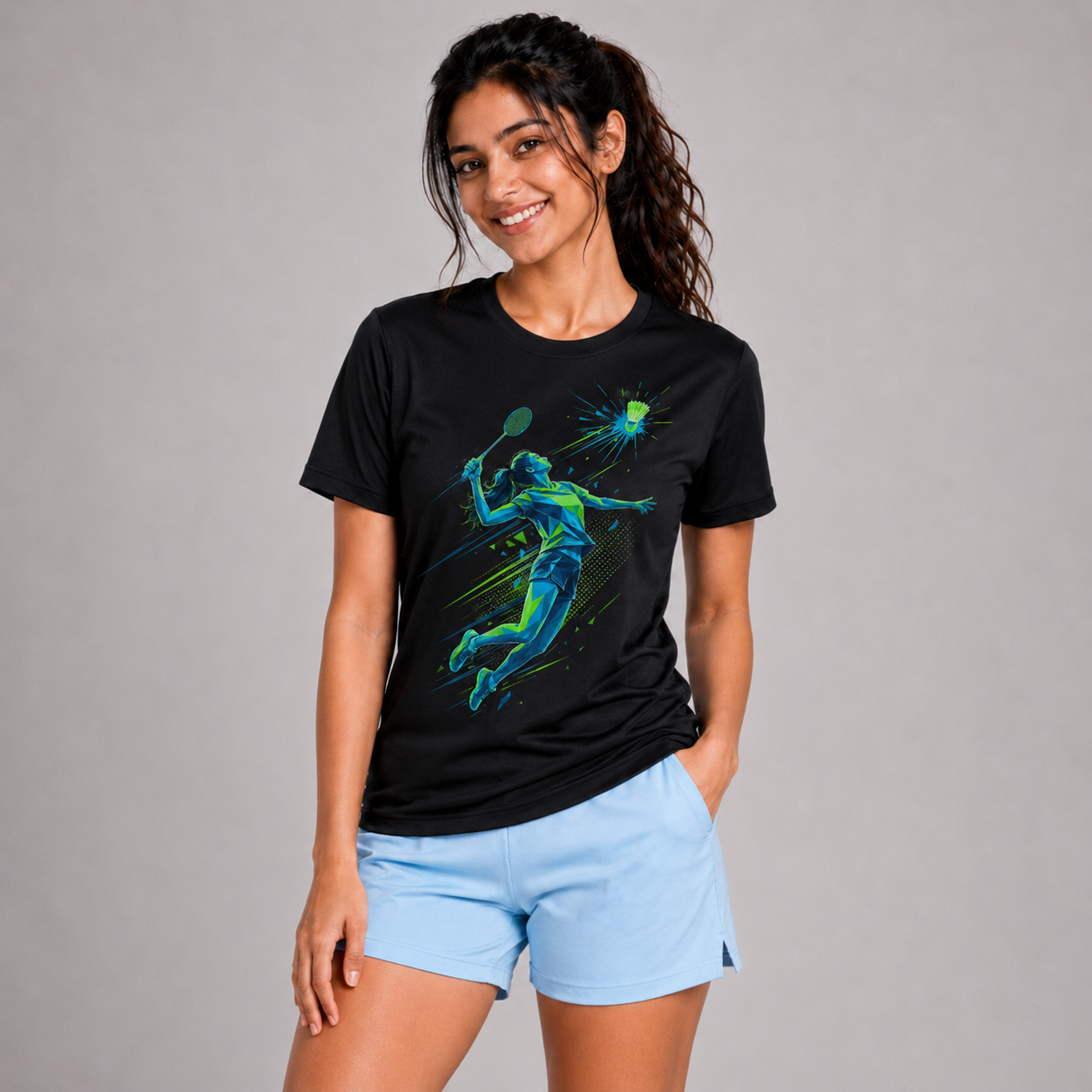 Woman wearing a black t-shirt with a badminton graphic design and light blue shorts on a gray background