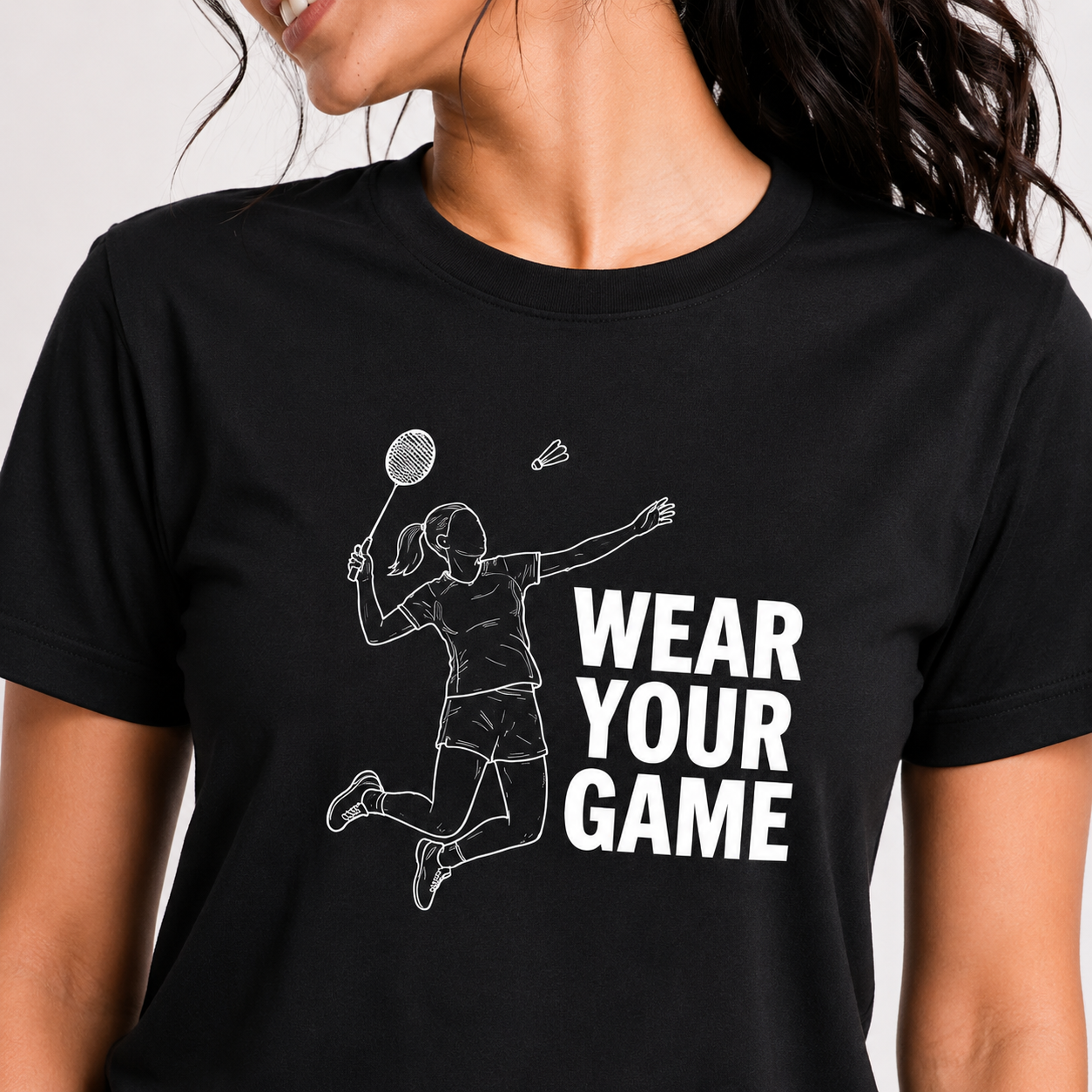 Black t-shirt with a graphic of a person playing badminton and the text 'Wear Your Game' on a plain background.