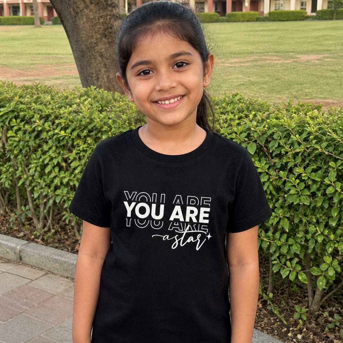 Young girl wearing a black t-shirt with motivational text in an outdoor setting