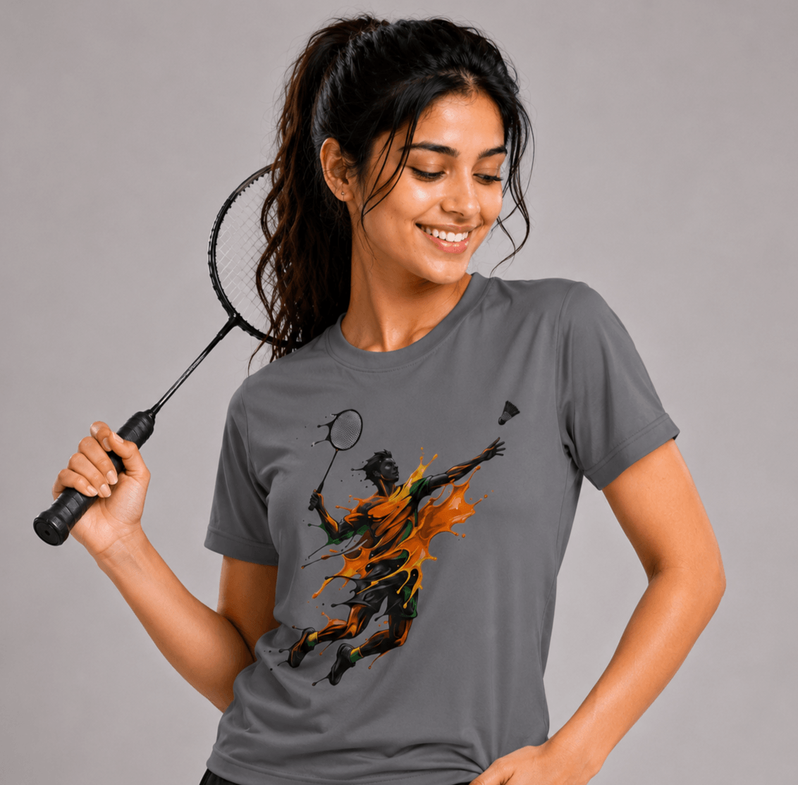 Woman wearing a gray t-shirt with a graphic design, holding a badminton racket.