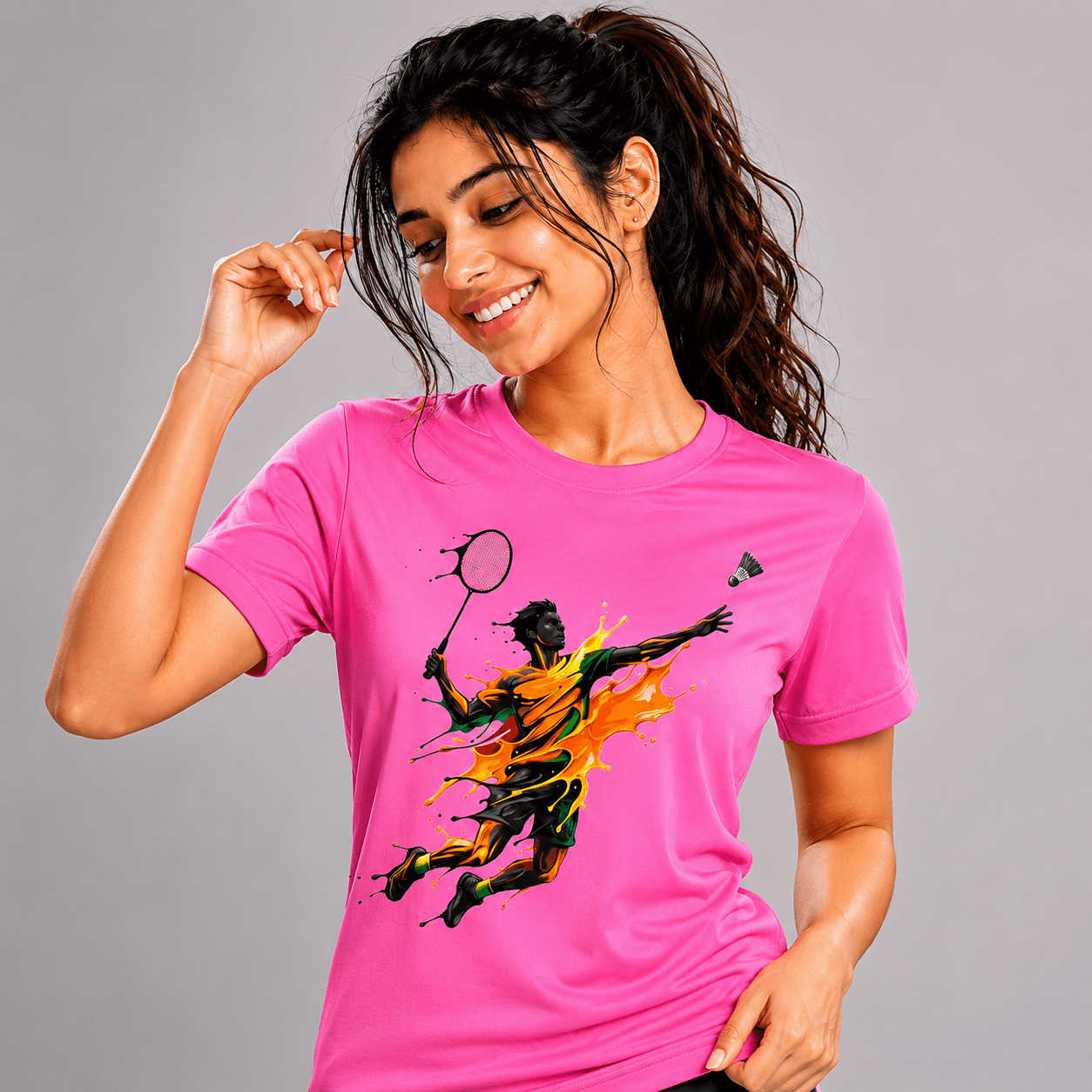 Woman wearing a pink t-shirt with a graphic design of a badminton player on a gray background