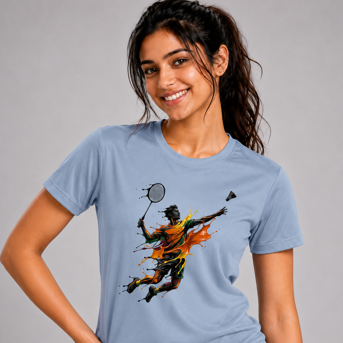 Woman wearing a light blue t-shirt with a colorful graphic design on a gray background