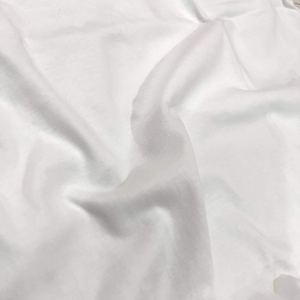 A close-up of draped white fabric with soft folds and a smooth texture.