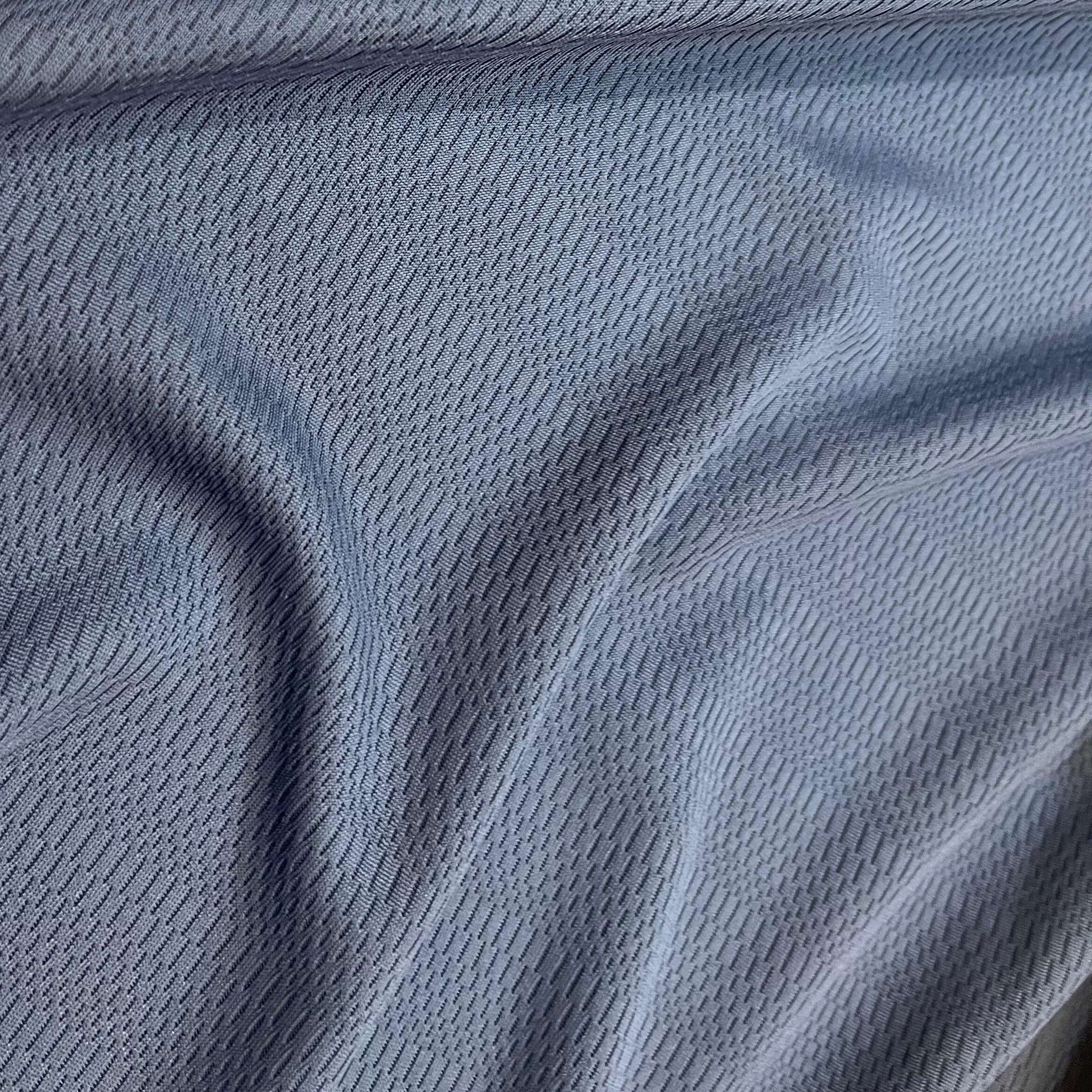 A close-up of a light blue-gray textured fabric with a fine mesh or woven pattern and soft folds.