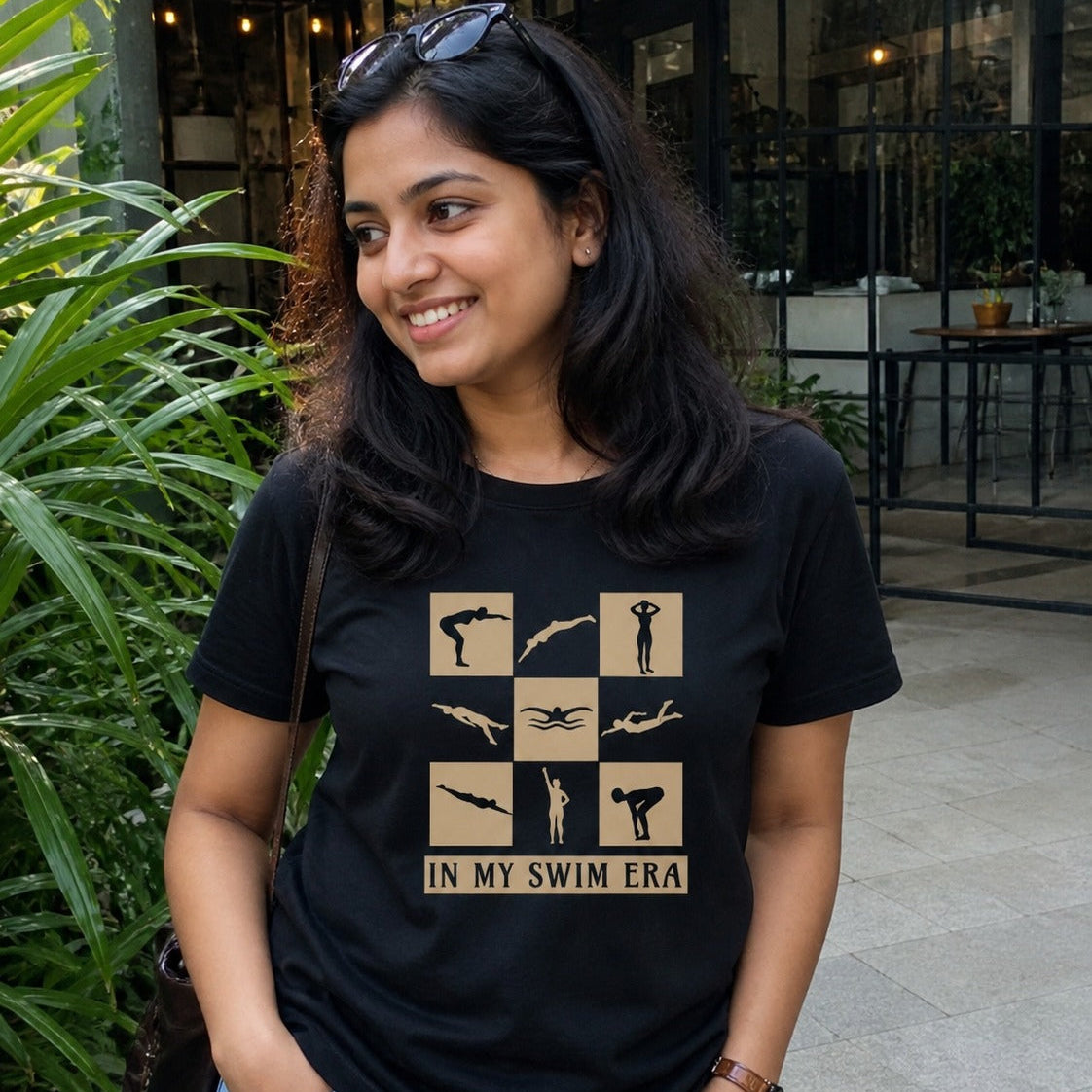 Woman wearing a black t-shirt with swim-themed design outdoors.