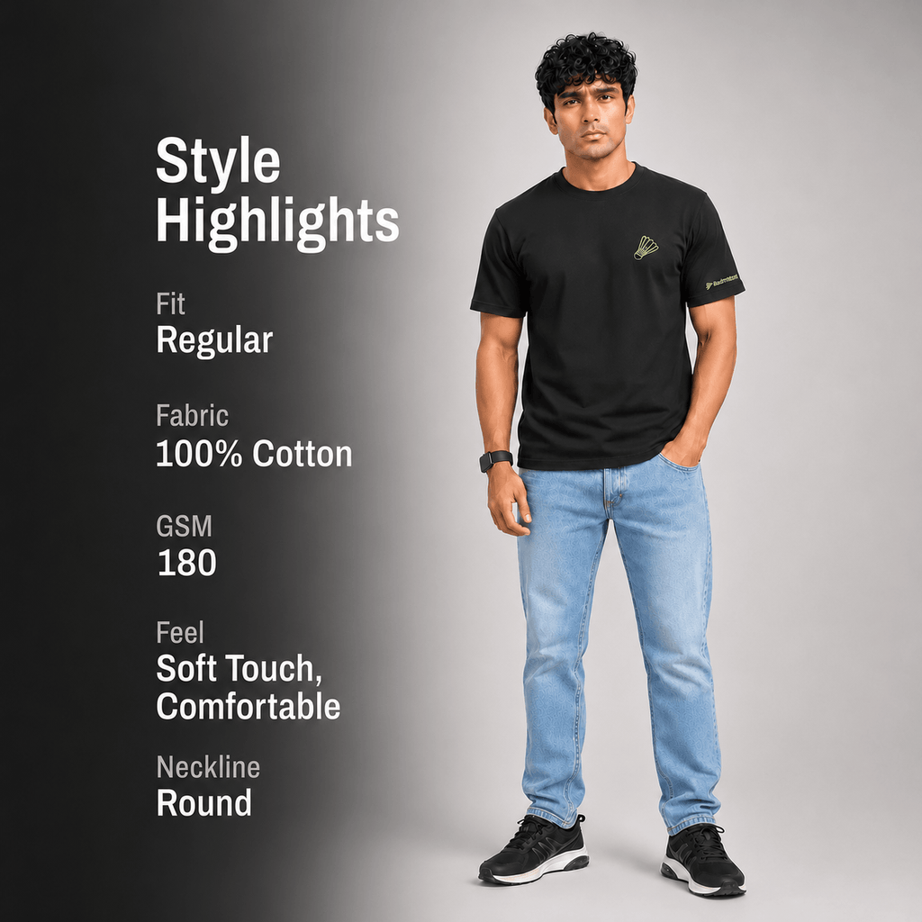 A man modeling a black short-sleeve t-shirt with light blue jeans and black sneakers, standing against a gray gradient background. On the left, white text reads 'Style Highlights' with details: Fit Regular, Fabric 100% Cotton, GSM 180, Feel Soft Touch, Comfortable, Neckline Round.